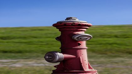 Vorschaubild eines alten Hydranten der vor einem Deich steht